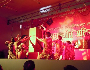 Dancers on stage with red background.