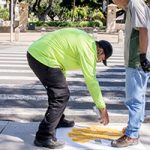 Commuter Services workers stenciling "Look All Ways" symbol on the sidewalk by the Dole Street crosswalk