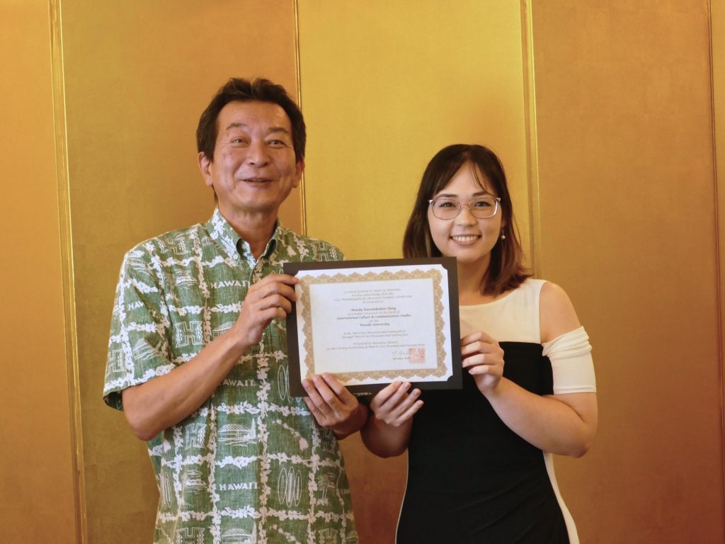 Consul General Yutaka Aoki on the left holding the MEXT research award certificate with award recipient, Melody Chung, on the right. 
