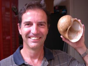 Dr. Robert Cowie holding a shell up to his face.