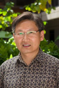 Dr. Tae-Ung Baik, Korean Man With Brown Diamond Square Pattern Collared Shirt And Wearing Glasses.