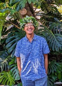 Herman Lim with lei in front of trees.