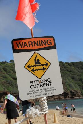 <p><strong>Fig. 5.18.</strong> A sign warns beach goers at Hanauma Bay, O‘ahu, Hawai‘i of the potentially strong longshore currents that flow parallel to shore.</p>
