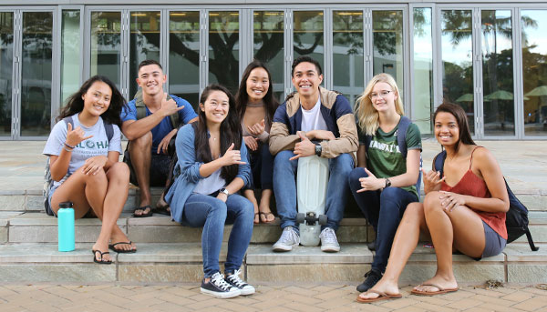 seven students sitting on the ground smiling at the camera