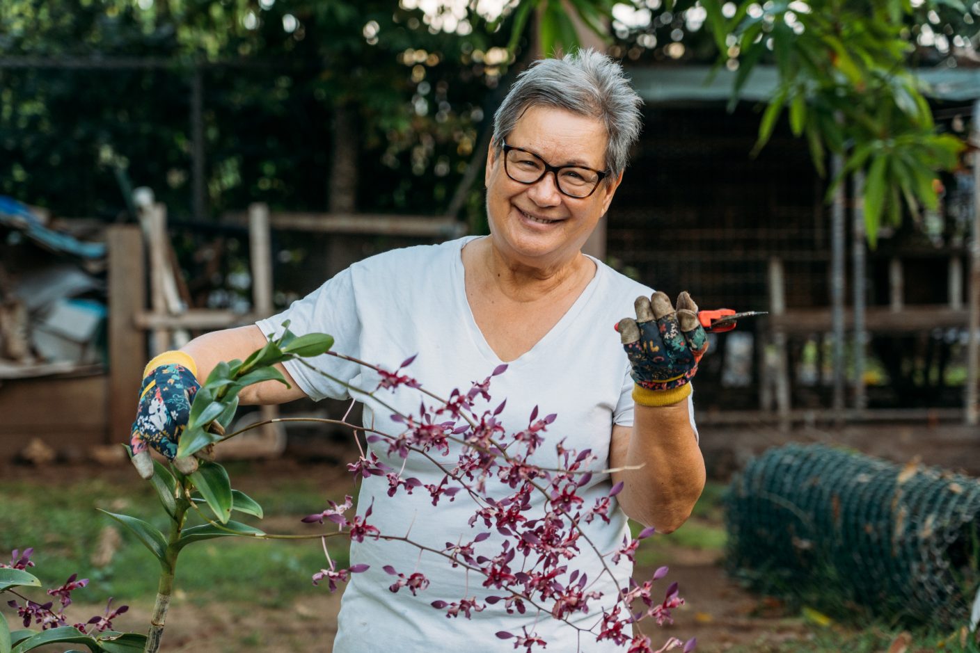 Native Hawaiian woman holding orchids and gardening clippers.