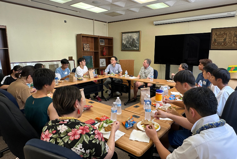 a group of students and staff sitting around the table for lunch and talking