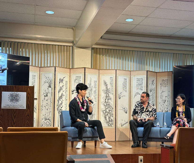 A moderator and two co-editors talk about a newly launched book at an auditorium