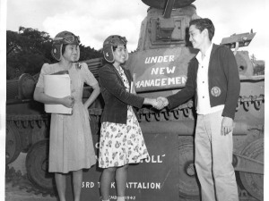 Students shaking hands in front of a tank