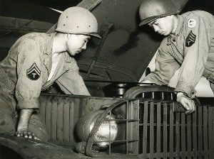 Photo of two soldiers in the 100th Infantry Battalion repairing a truck during training.