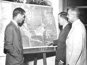 G. W. Fisher and Charles F. Loomis listen as James H. Shoemaker points to map of Netherlands (Dutch) East Indies at Report of 10th IPR Conference, Montague Hall, Punahou School, 6 Oct. 1947.