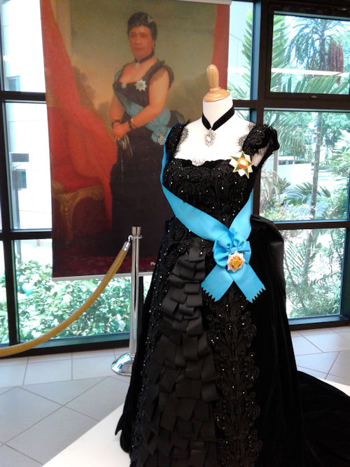Queen Liliʻuokalani's dress in front of a painting of her in the dress