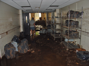 Muddy floors inside the building with equipment in trash bags