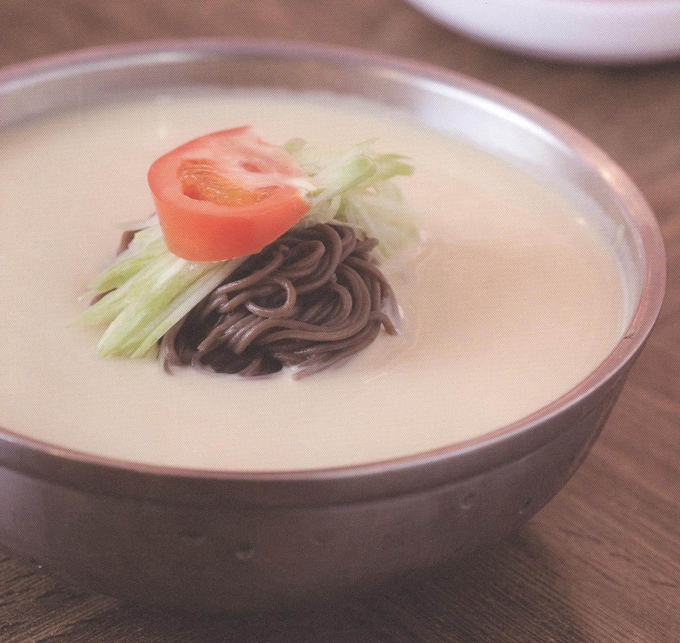 Dark noodles in a white sauce with a tomato slice on top