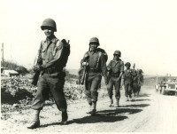 Soldiers marching along dirt road