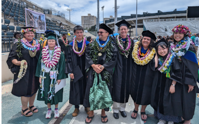 Our spring graduates standing outside with lei and regalia