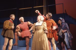 Georgia Engel in Elizabethan costume performing on stage in Romeo and Juliet, surrounded by male actors.