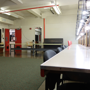 Open Area With Carpet And Polished Cement Floor. Large Table. Door Sized Mirror.