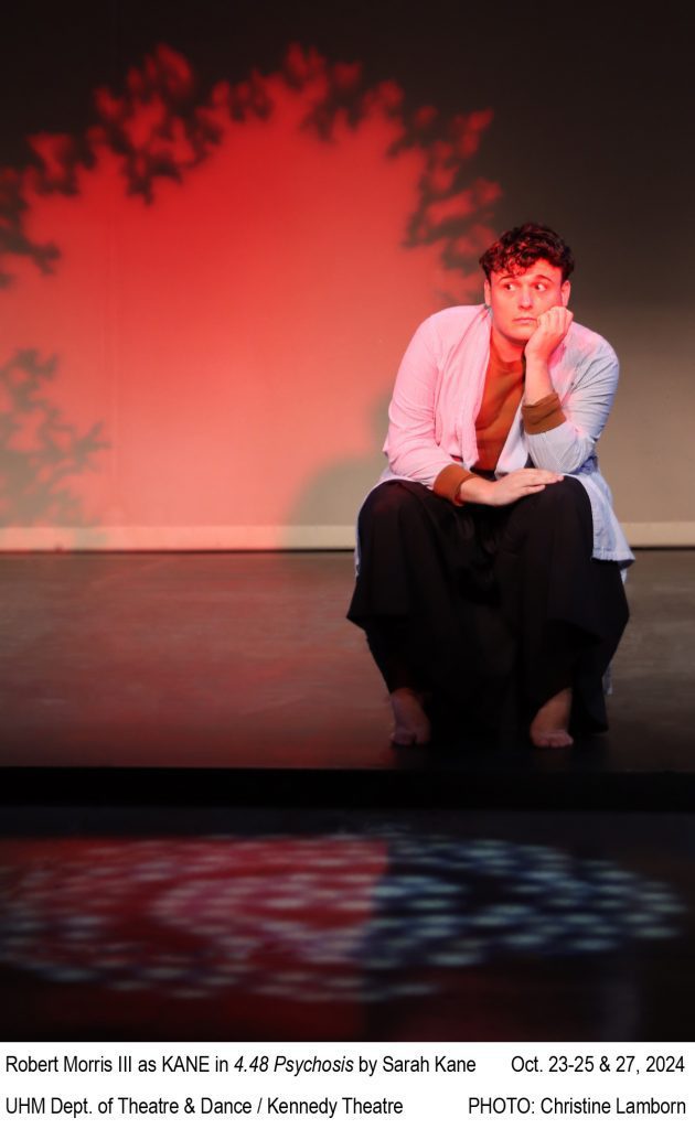 Image of a college actor sitting with elbows resting on the knees and head rest on a hand. Res lighting illuminates the actor and background. TEXT: Robert Morris III as KANE in 4.48 Psychosis by Sarah Kane. October 23-25 & 27, 2024. UHM Dept. of Theatre & Dance / Kennedy Theatre. PHOTO: Christine Lamborn.