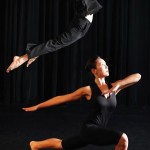 Photo of two dancers; one lunges the other jumps in the air with arched back