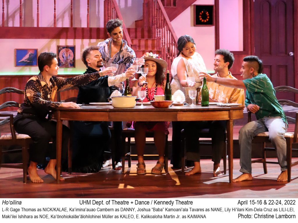 5 college actors sit at a dining table, 2 stand in the back. Everyone is engaged in a "cheers". TEXT: Ho‘oilina. UHM Dept. of Theatre + Dance / Kennedy Theatre. April 15-16 & 22-24, 2022 L-R Gage Thomas as NICK/KALAE, Kaʻiminaʻauao Cambern as DANNY, Joshua “Baba” Kamoaniʻala Tavares as NANE, Lily Hiʻilani Kim-Dela Cruz as LILI-LEI,  Makiʻilei Ishihara as NOE, Kaʻōnohiokalāeʻālohilohinei Müller as KALEO, E. Kalikoaloha Martin Jr. as KAIMANA. Photo: Christine Lamborn.