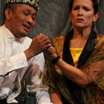 Two performers; one wears a crown and is holding/looking at the others hand