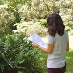 A woman stands in the garden reading a map