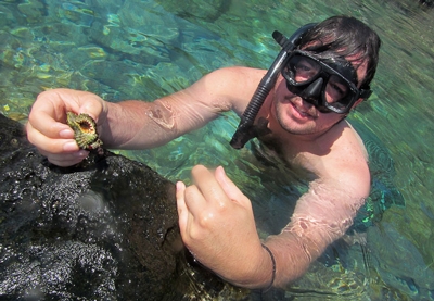 Snorkeler in tide pool holding a snail