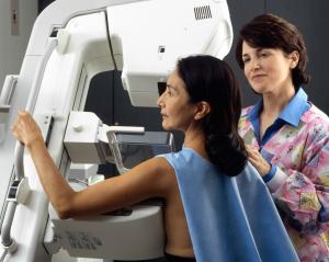 A tech assists a patient at an imaging machine to receive a mammogram. PC: National Cancer Institute