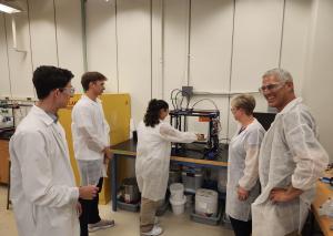 Students and mentors demonstrate a system’s material science applications for visitors. Credit: UHM