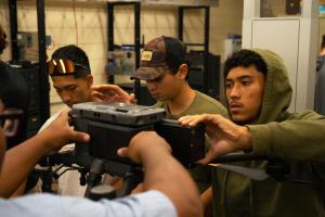 (L-R) Isaac Mandaloniz, Thomas Costa and Khayden Kahihikolo insert batteries in the DJI Matrice 350 