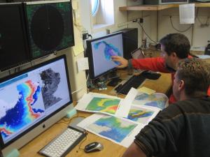 Researchers assess bathymetry maps during a research cruise in the Pacific Ocean. Credit: UMD.