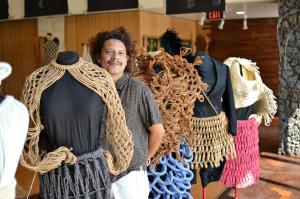 Hawai'i CC Professor Dr. Taupouri Tangaro stands with examples of the regalia he created.