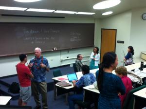 Bramlett (standing, with lei) and Wizner, seated, meet with students and the public during a break.