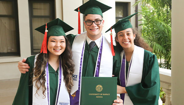 three graduated students holding their diploma