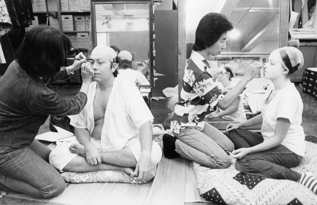 Onoe Kikunobu (Gertrude Tsutsumi, right) and Howard Asao (Onoe Kikunobukazu) apply makeup on students.