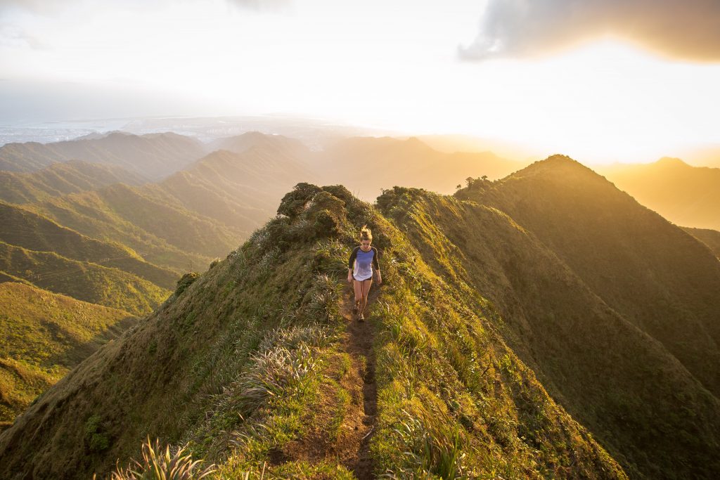 Woman walking on trail in the mountains at sunset