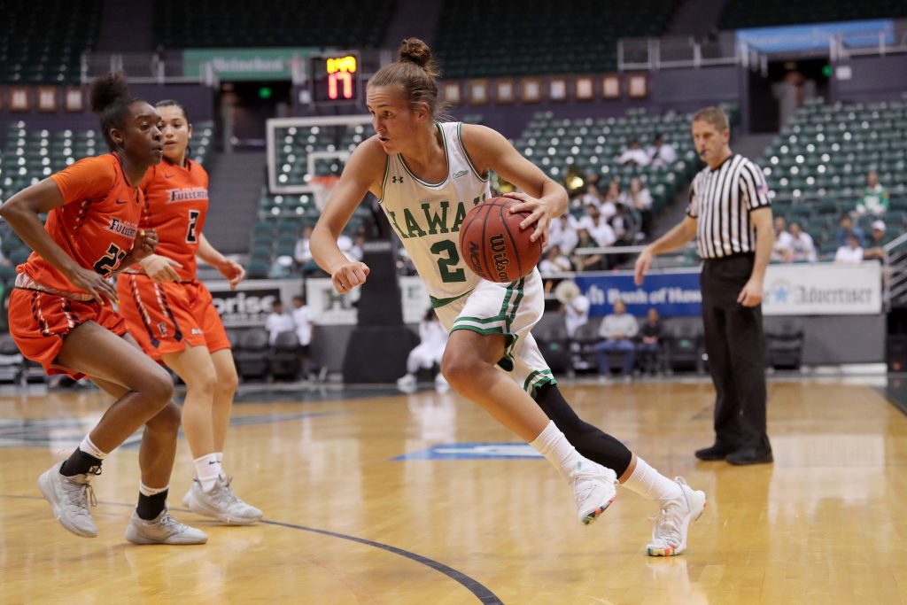 Univeristy of Hawaii at Manoa Wahine Basketball Player Dribbling a ball around an opponent