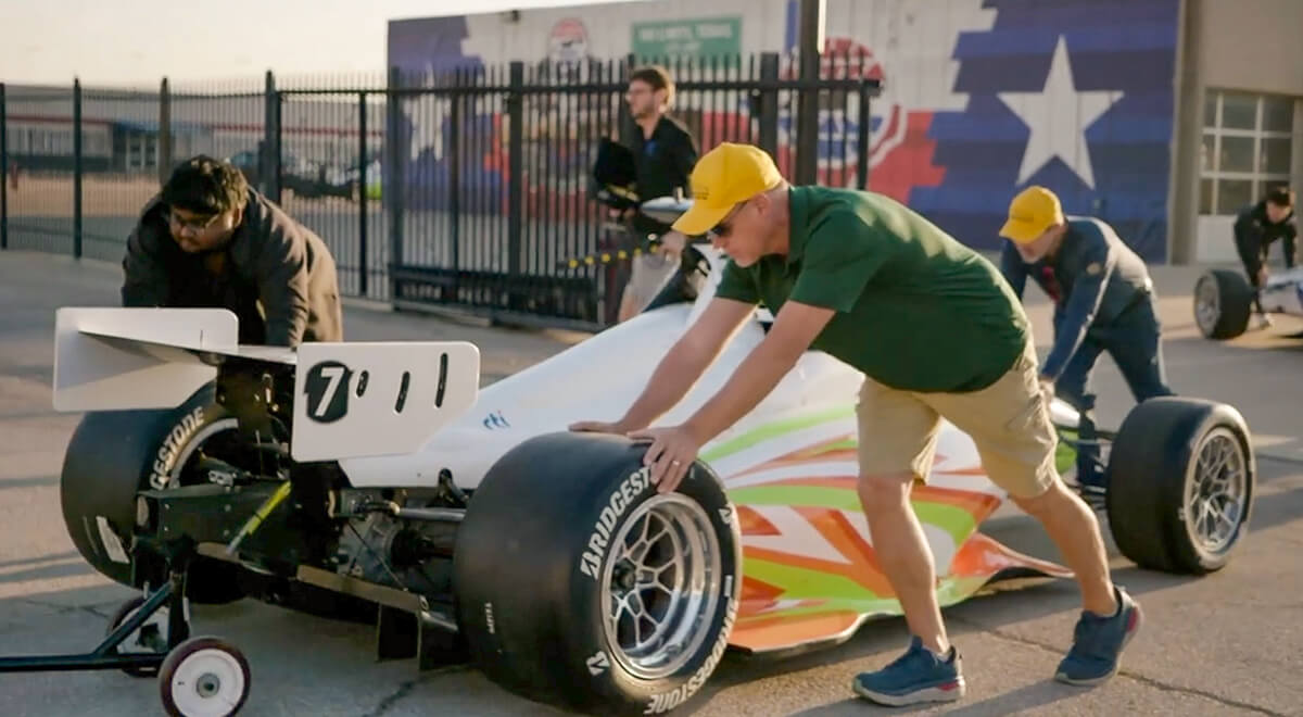 The UH AI Racing Tech team members push their vehicle toward its towing device