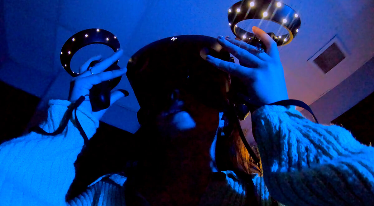 Student wearing a virtual reality (VR) headset and using two joysticks