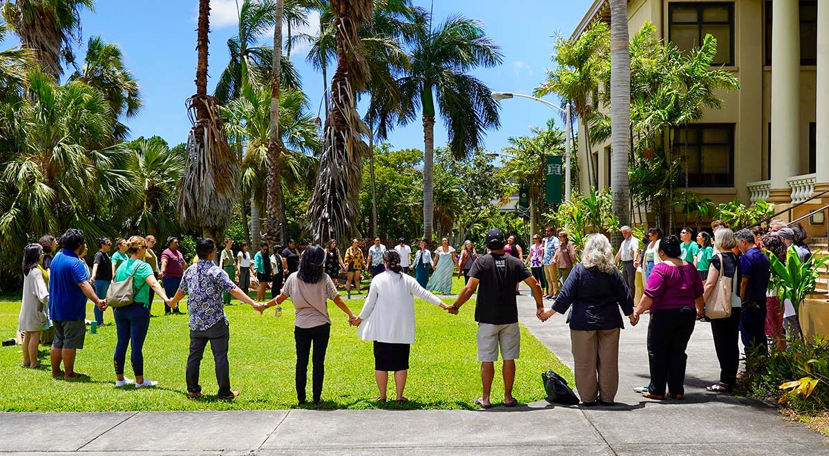 More than 50 people from the University of Hawaii at Mānoa community gathered in a circle in front of Hawaii Hall, and holding hands to hold a ceremony for Maui